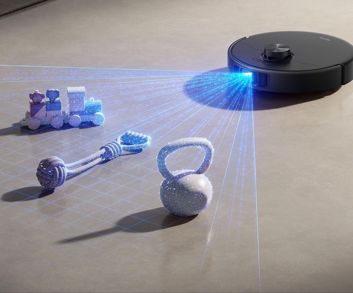 Der schwarze MOVA P70 Pro Ultra tastet mit blauem Lichtfächer Spielzeugzug, Hundespielzeug und Kettlebell auf dem Boden ab.