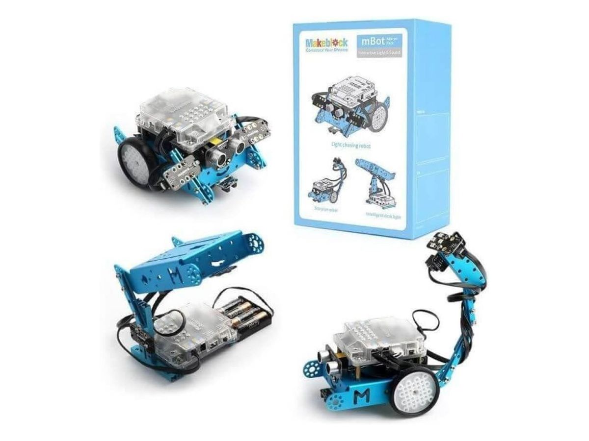 Lichtfolger, Schreibtischlampe und Skorpion aus mBot und Erweiterungsteilen neben der hellblauen Schachtel des Interactive Light & Sound Pack.