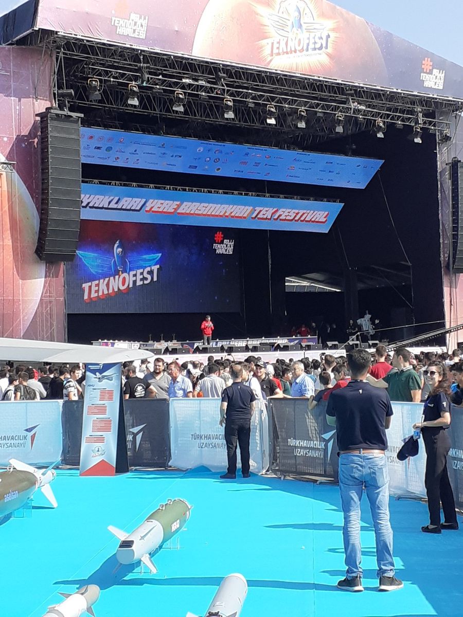 Mann im dunklen Anzug am Rednerpult vor blauem Hintergrund, mit Mikrofon in der Hand