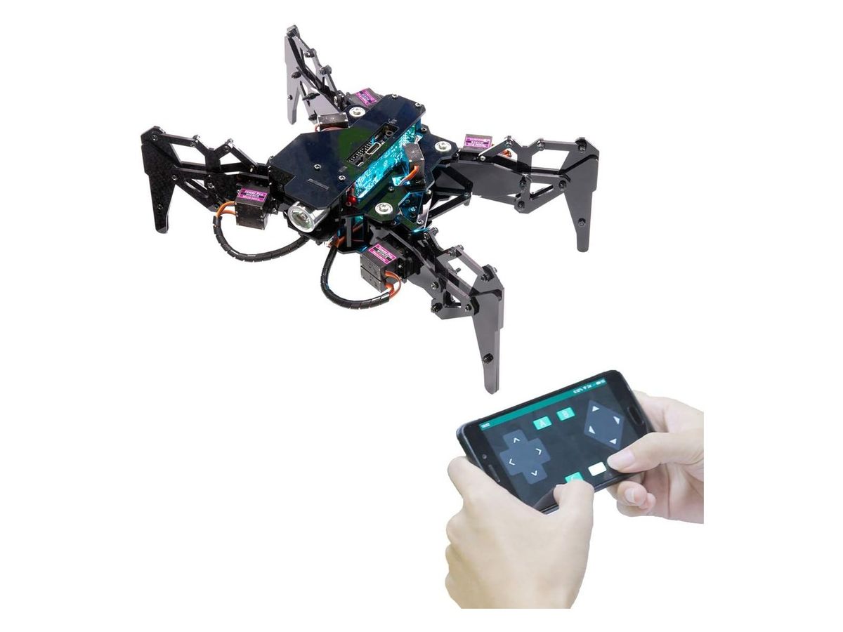 Ältere Ausführung des DarkPaw: schwarzer vierbeiniger Spinnenroboter aus Acryl mit Servos und Scheinwerfer, darunter zwei Hände mit einem Smartphone und Steuer-App.