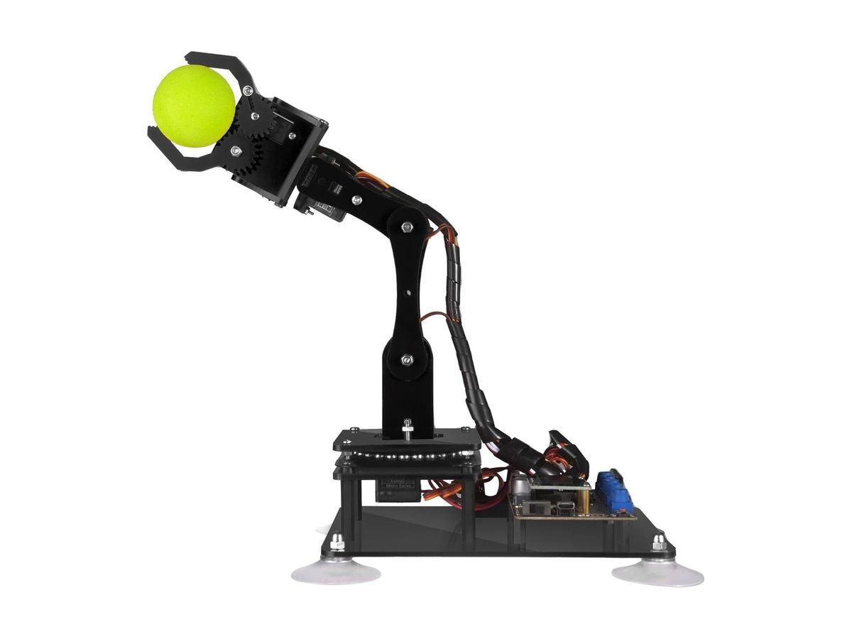 Schwarzer Acryl-Roboterarm mit Zahnradgreifer, der einen gelben Schaumstoffball hält, auf einer Grundplatte mit Saugnäpfen und Steuerplatine.
