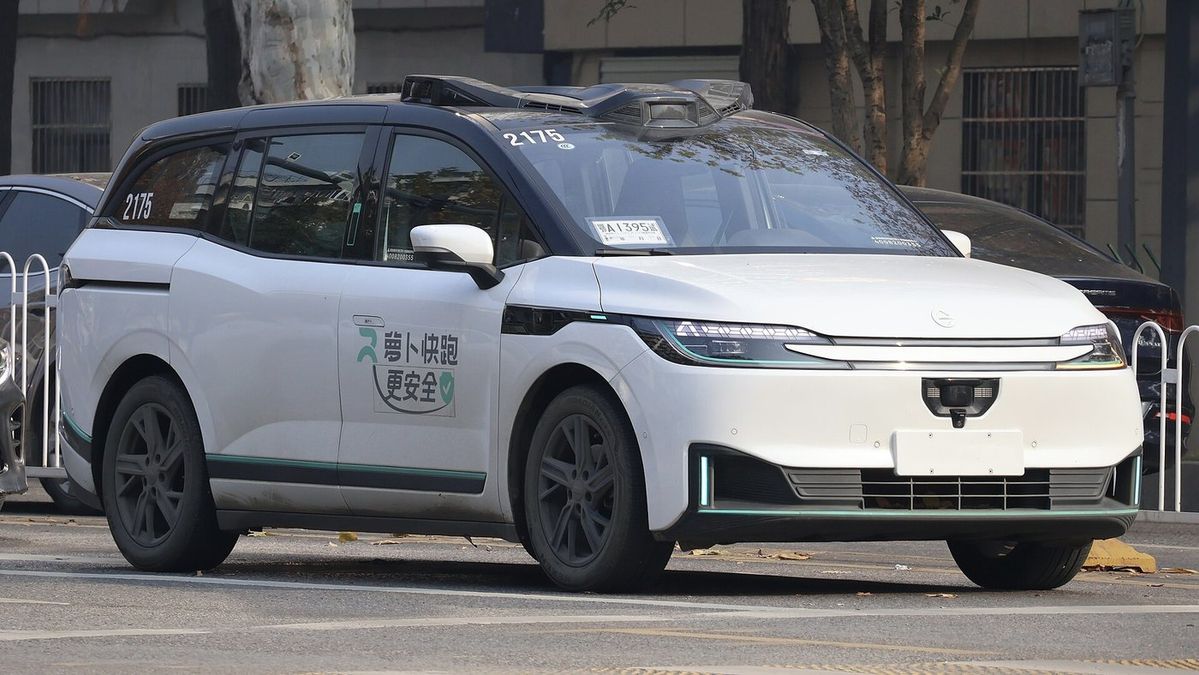 Weißer Elektro-Van mit schwarzem Dach und Sensoraufbau auf einer Straße in Wuhan, an der Tür chinesische Schriftzeichen und ein grünes Logo, an der Windschutzscheibe die Nummer 2175
