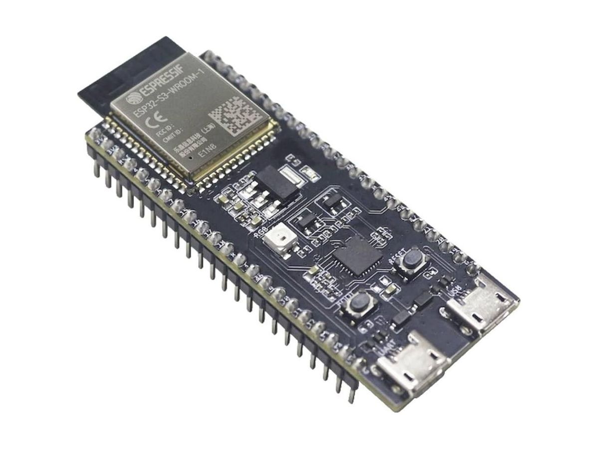 Schwarze Platine des ESP32-S3-DevKitC-1 schräg von oben mit ESP32-S3-WROOM-1-Modul, RGB-LED, BOOT- und RESET-Taster sowie zwei Micro-USB-Buchsen.