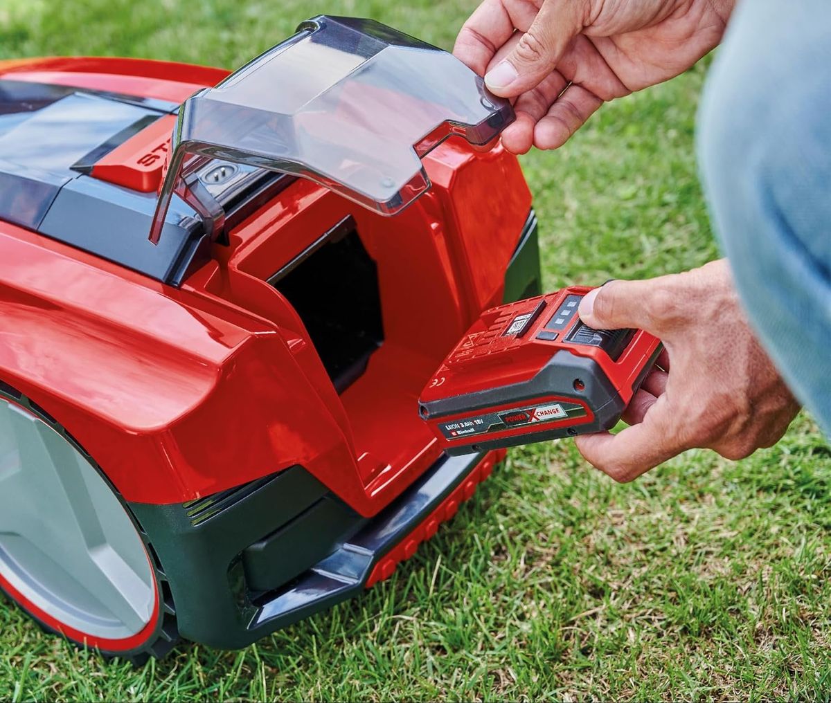 Hände heben die transparente Klappe eines roten Einhell-FREELEXO-Mähroboters an und ziehen den Power-X-Change-Akku aus dem Fach – Bild des baugleichen FREELEXO SMART 750.