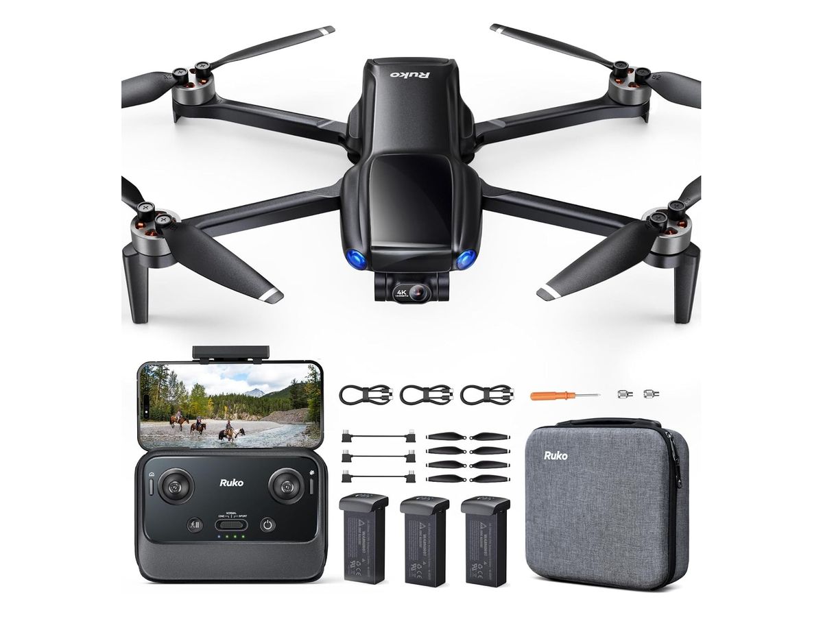Schwarze Quadrocopter-Drohne mit Ruko-Schriftzug und Gimbal-Kamera von oben, darunter Fernsteuerung mit eingesetztem Smartphone, drei Akkus, Propeller, Kabel und graue Tragetasche.