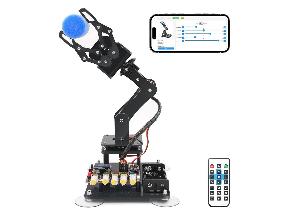 Schwarzer Acryl-Roboterarm mit Gestängegreifer, der einen blauen Schaumstoffball hält, auf einer Grundplatte mit Saugnäpfen, Steuerplatine mit OLED-Anzeige und gelben Drehknöpfen sowie Akkuhalter; daneben ein Smartphone mit Steuer-App und eine IR-Fernbedienung