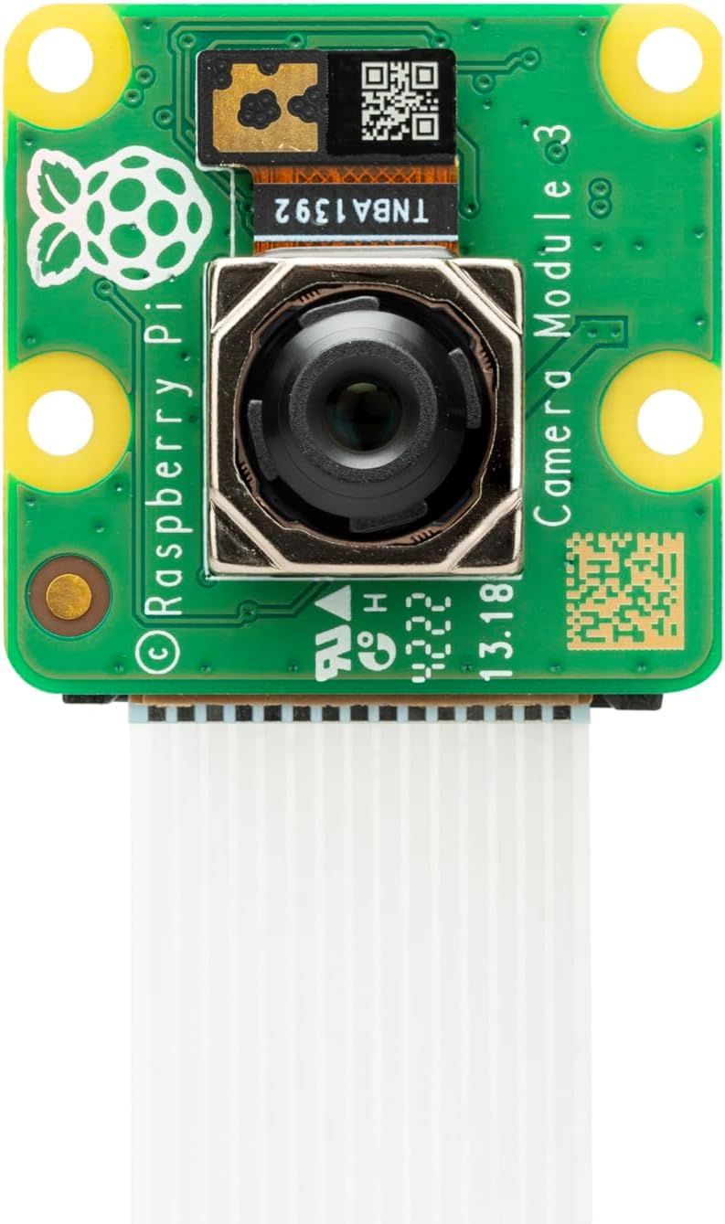 Quadratische grüne Kameraplatine „Camera Module 3“ mit Autofokus-Objektiv in Metallrahmen und weißem Flachbandkabel.