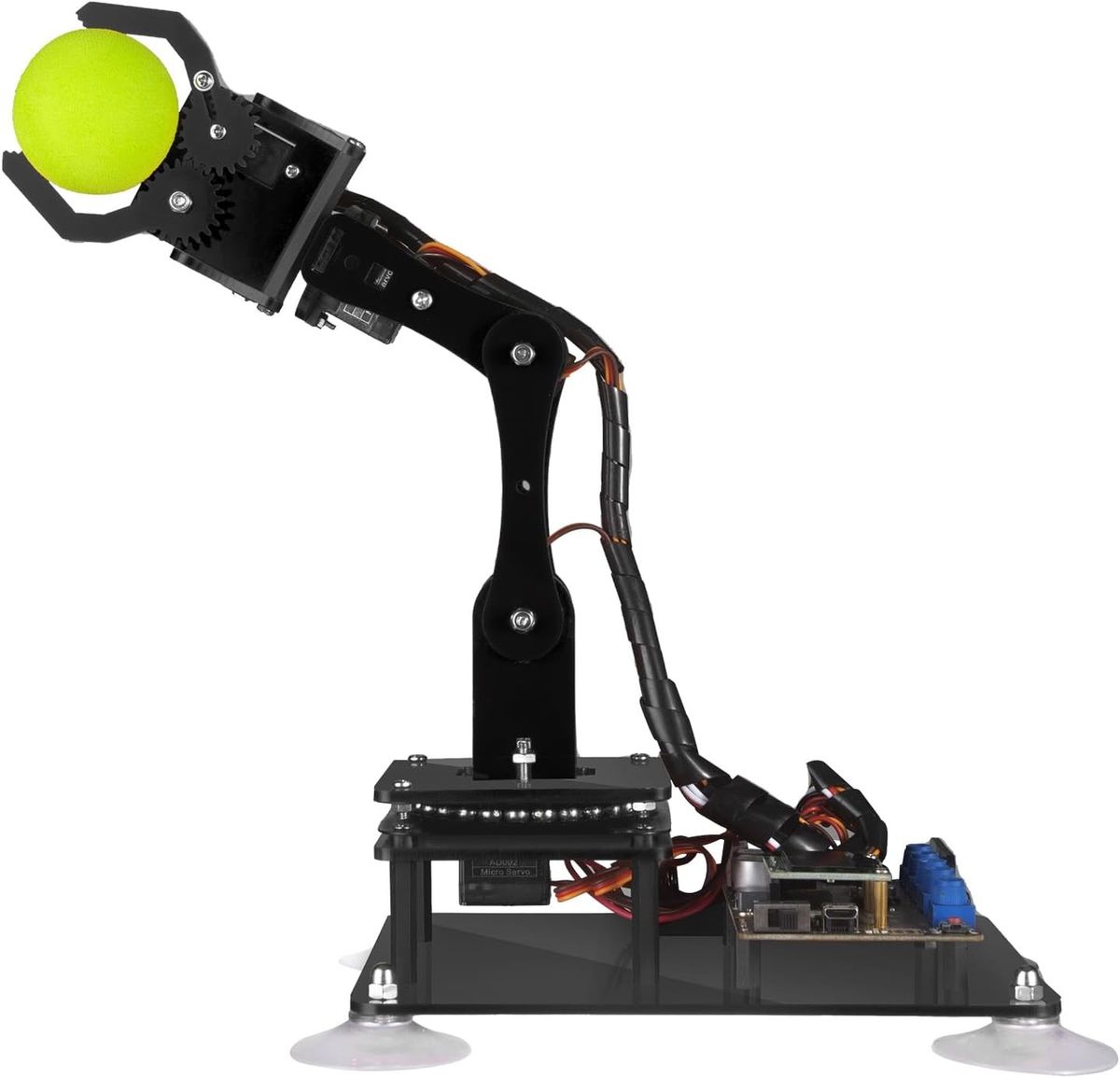 Schwarzer Acryl-Roboterarm mit Zahnradgreifer, der einen gelben Schaumstoffball hält, auf einer Grundplatte mit Saugnäpfen und Steuerplatine.
