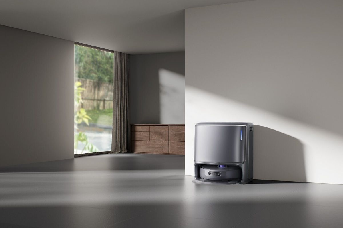 Graue Basisstation des Narwal Freo Z10 Ultra mit eingedocktem Roboter an einer hellen Wand in einem minimalistischen Wohnraum.